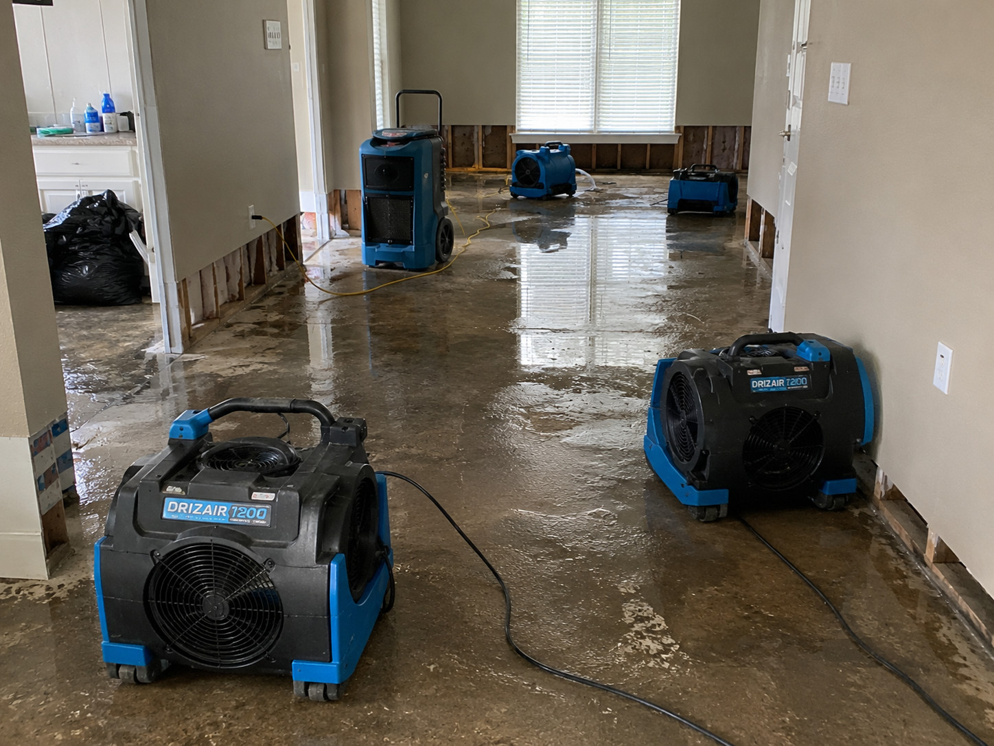 Professional water damage restoration equipment drying the floors and exposed wall cavities inside a home after water intrusion to help prepare the property for repairs.