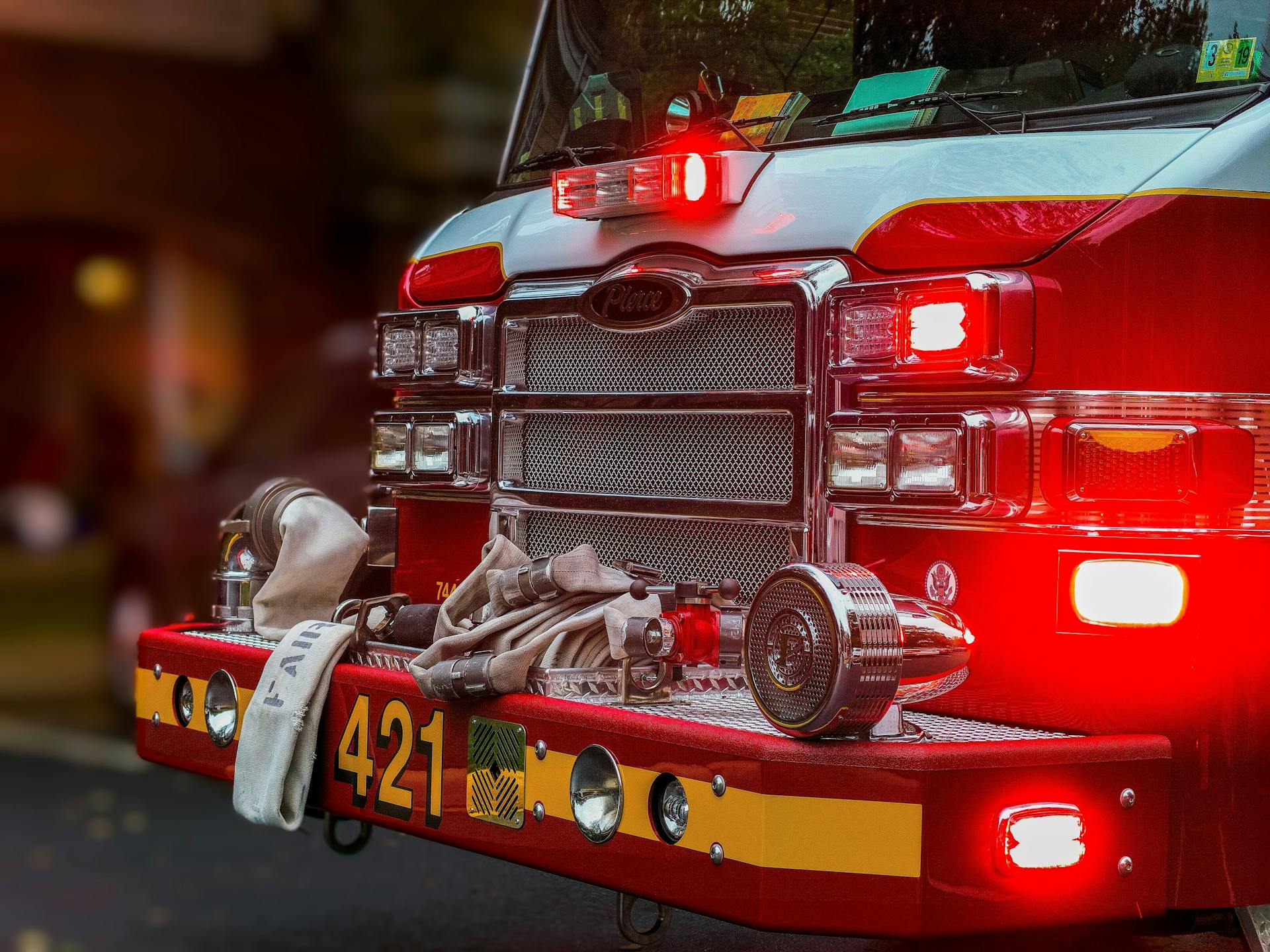 Close-up of a fire engine with illuminated emergency lights, fire hoses, and firefighting equipment parked and ready for emergency response.